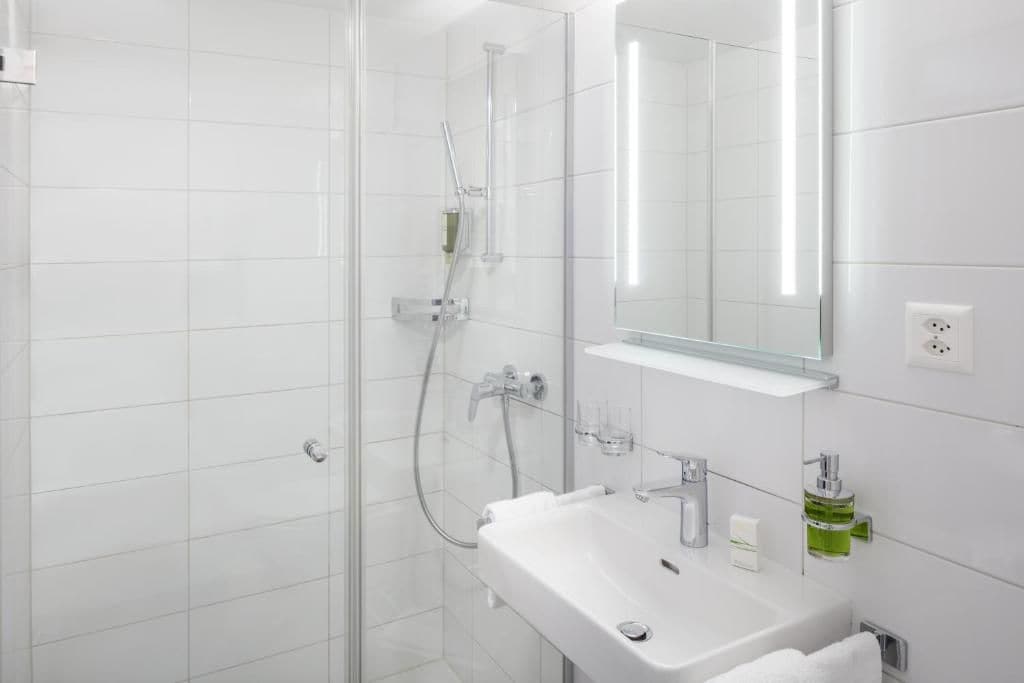 A modern bathroom with a glass shower enclosure, a white sink, and a mirror above it.