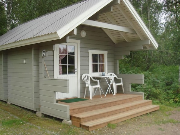 Une petite cabane avec une véranda, deux fenêtres et une porte.