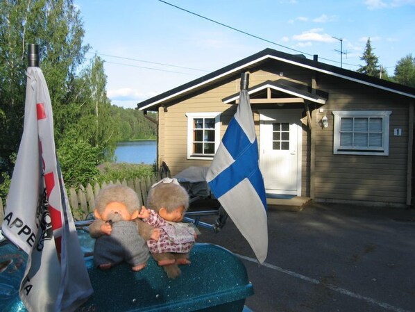 A small house with a dock, a flag, and two children playing.