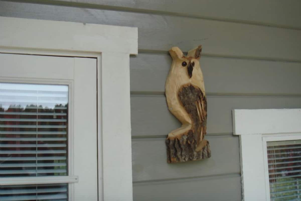 A wooden owl decoration mounted on a house exterior.