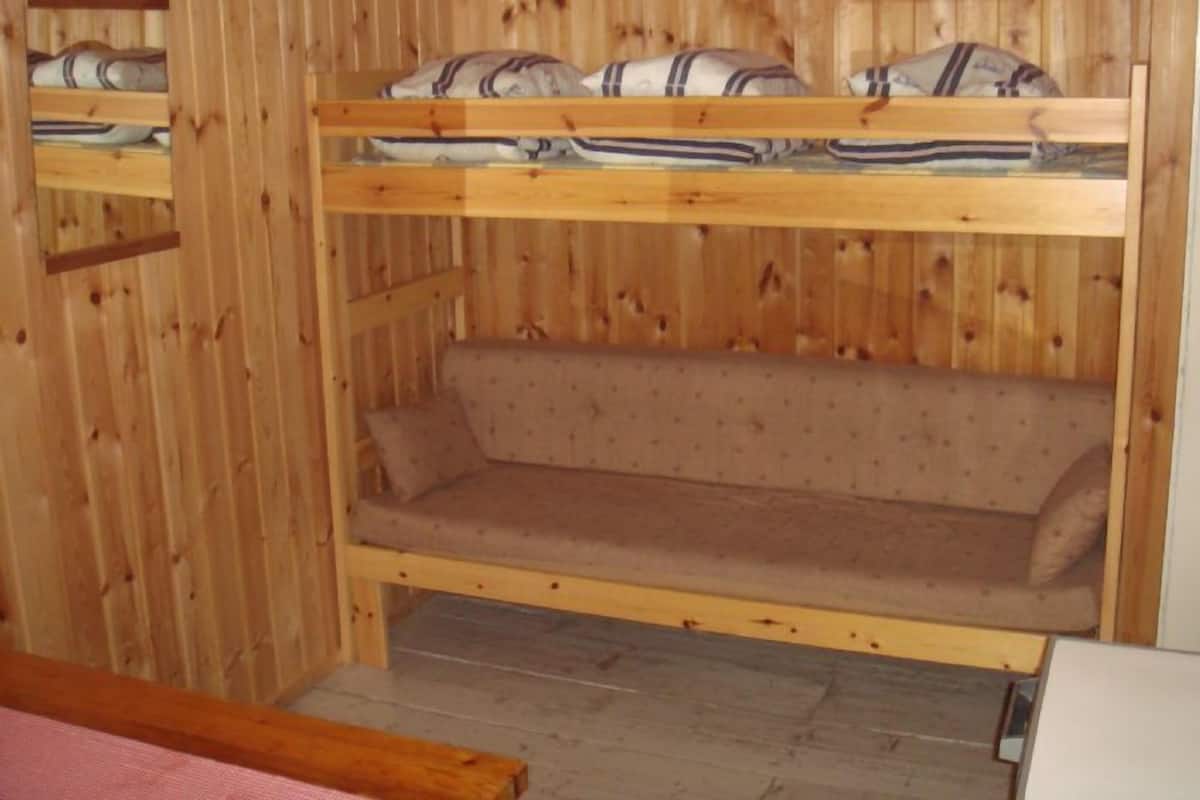 A bunk bed with a lower bunk and a sofa bed in a wooden room.