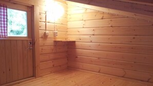 Une pièce aux murs lambrissés, dotée d’une porte, d’une fenêtre et d’un luminaire.