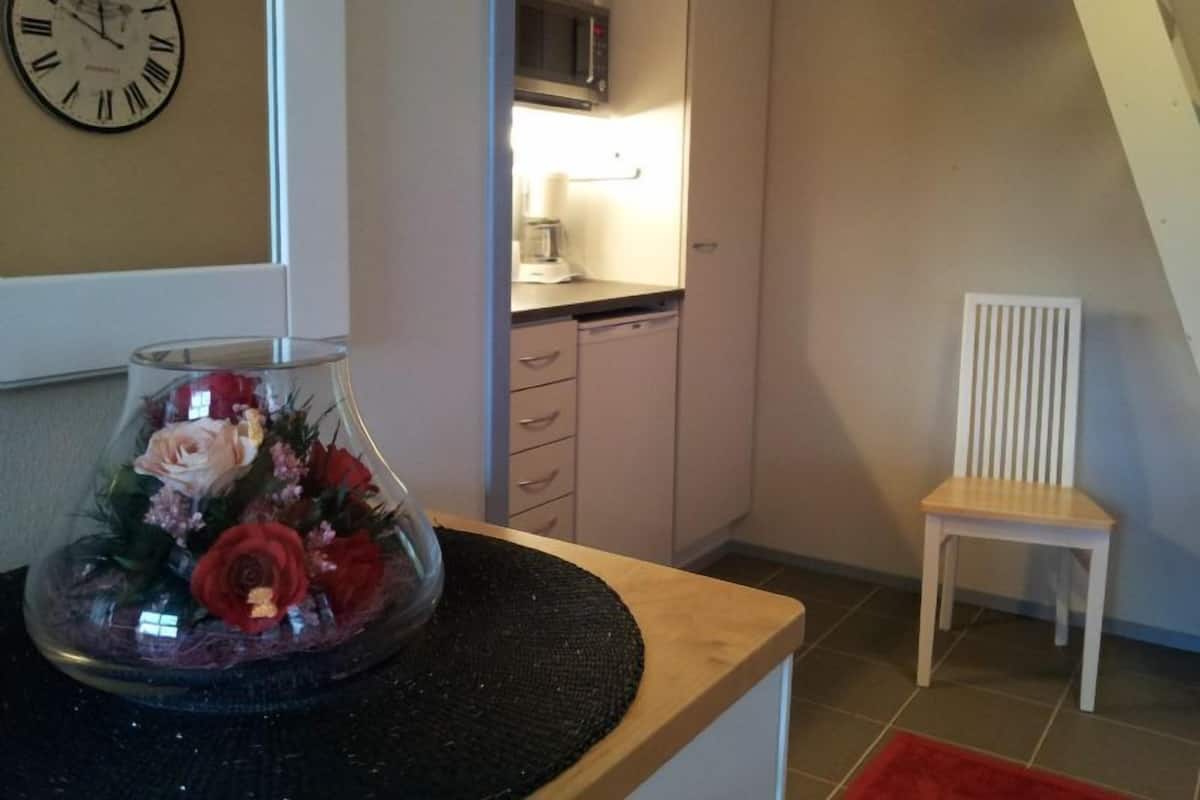 A kitchen with a microwave, a coffee maker, and a chair.