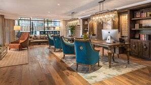 Uma sala de estar ampla com piso de madeira, um sofá, uma mesa de jantar com cadeiras e uma escrivaninha com um computador.