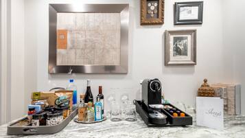 A kitchen counter with a coffee machine, wine bottles, and a tray of snacks.