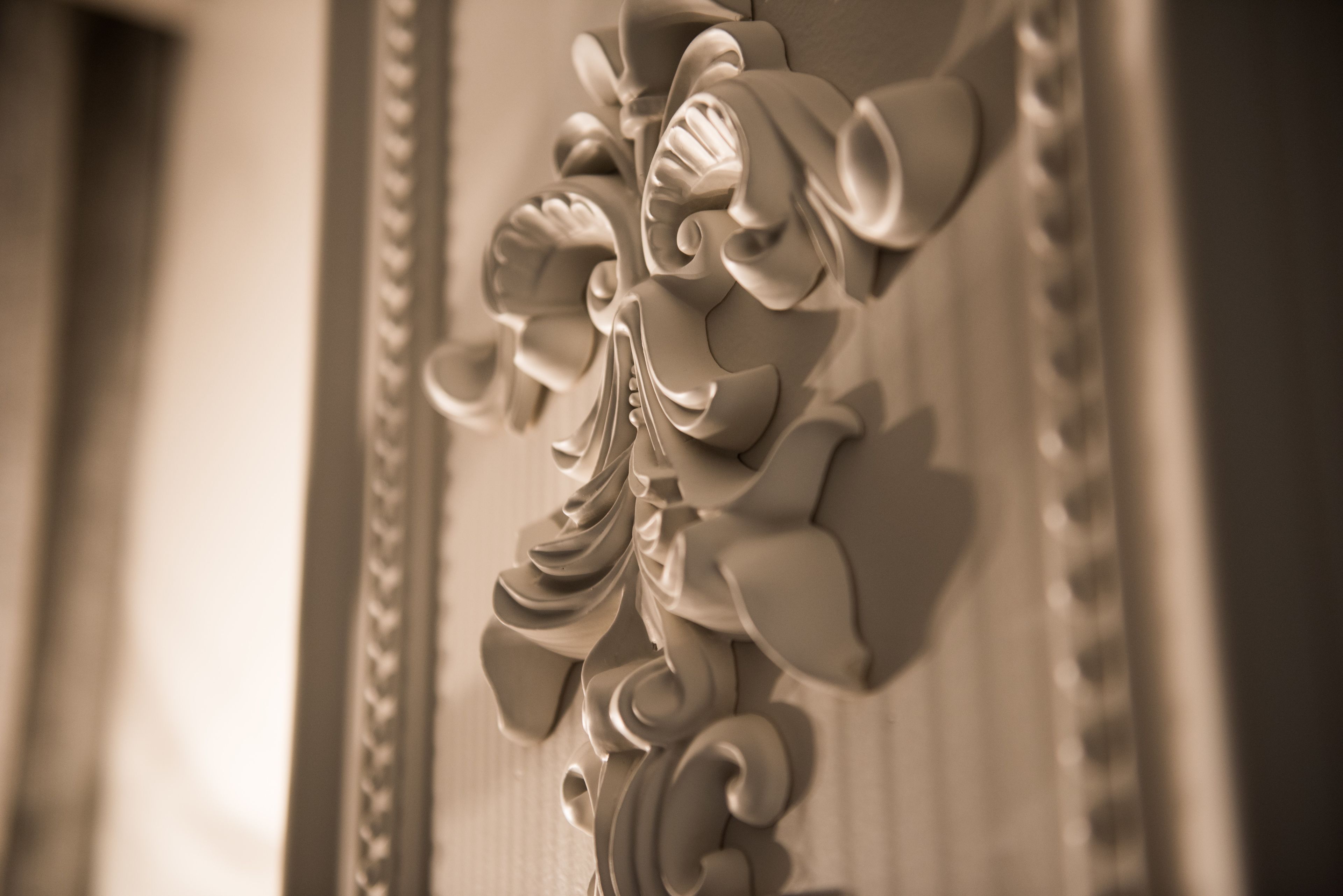 A close-up of a wall with ornate, carved floral and scroll designs.