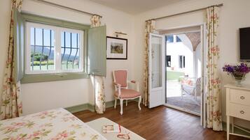 A room with a bed, a chair, a desk, and a door leading to an outdoor area.