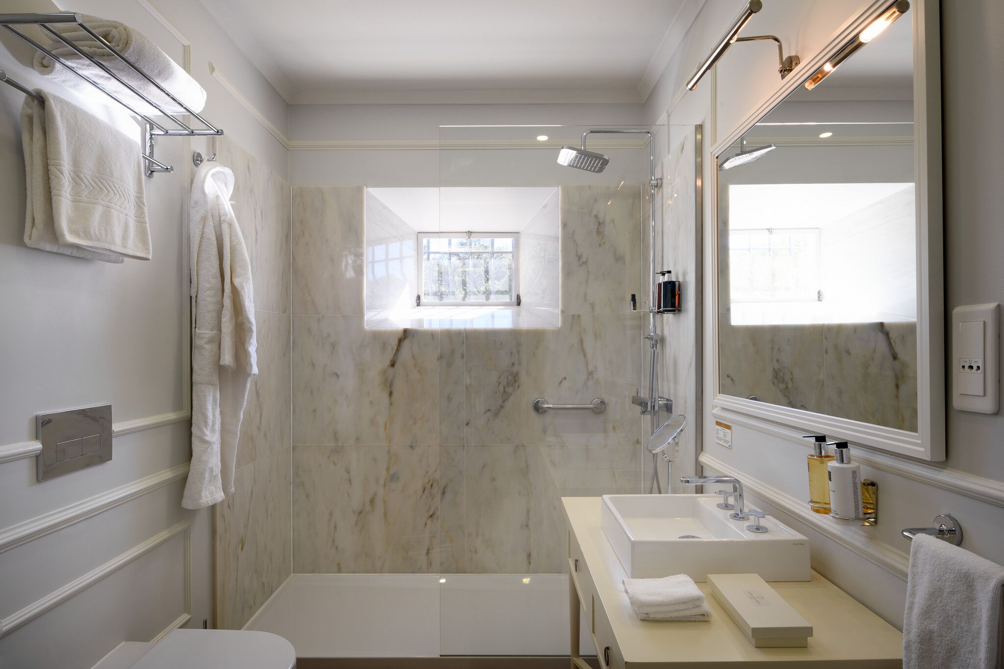 A modern bathroom with a large mirror, a bathtub, a shower, and a vanity with a sink.