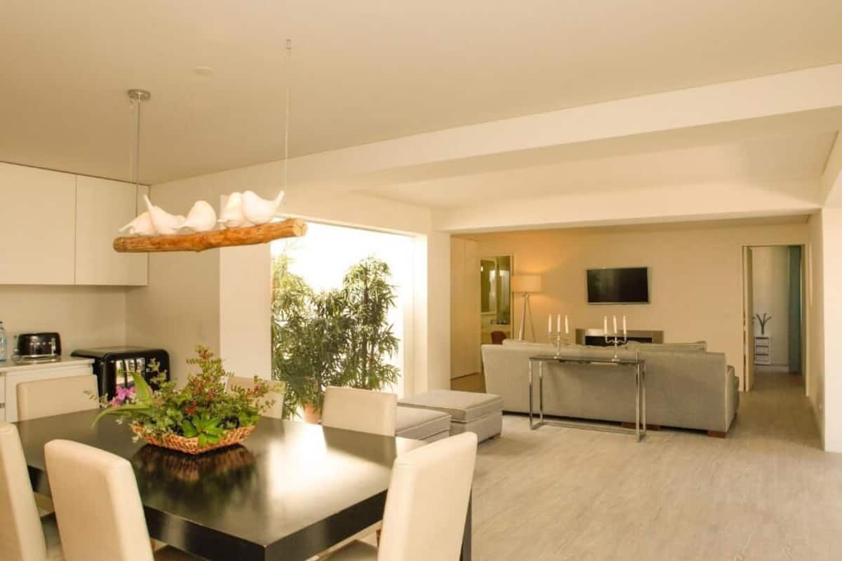 A modern living space with a dining area, sofa, and TV.