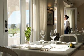 A dining table set with plates, cutlery, and glasses, with a potted plant and a lemon on the table. - Hotel Casa Palmela (Setubal)