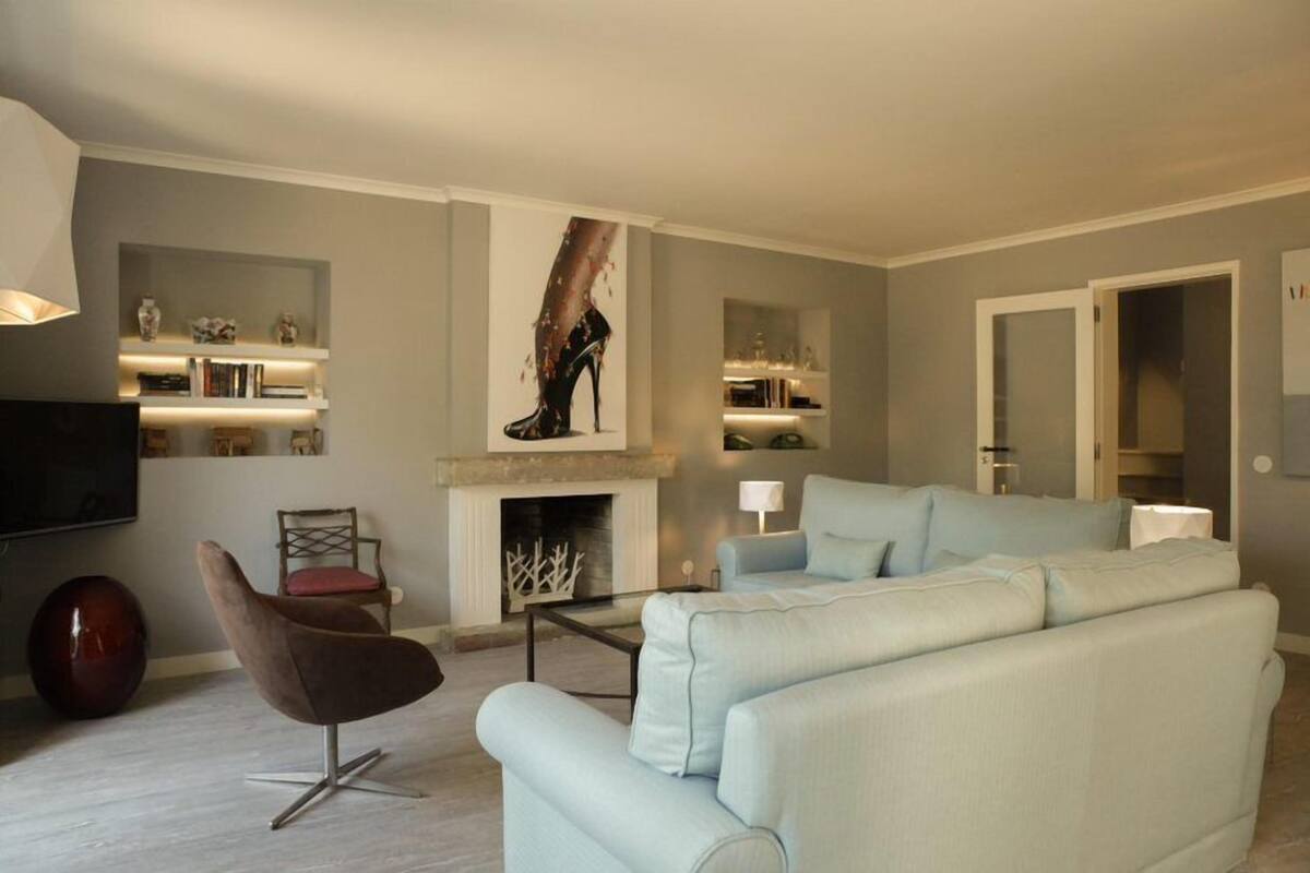 A modern living room with a sofa, a chair, a fireplace, and shelves with decorative items.