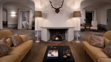Ein gemütliches Wohnzimmer mit Kamin, zwei Sofas und einem Couchtisch mit einem Buch und Gläsern.