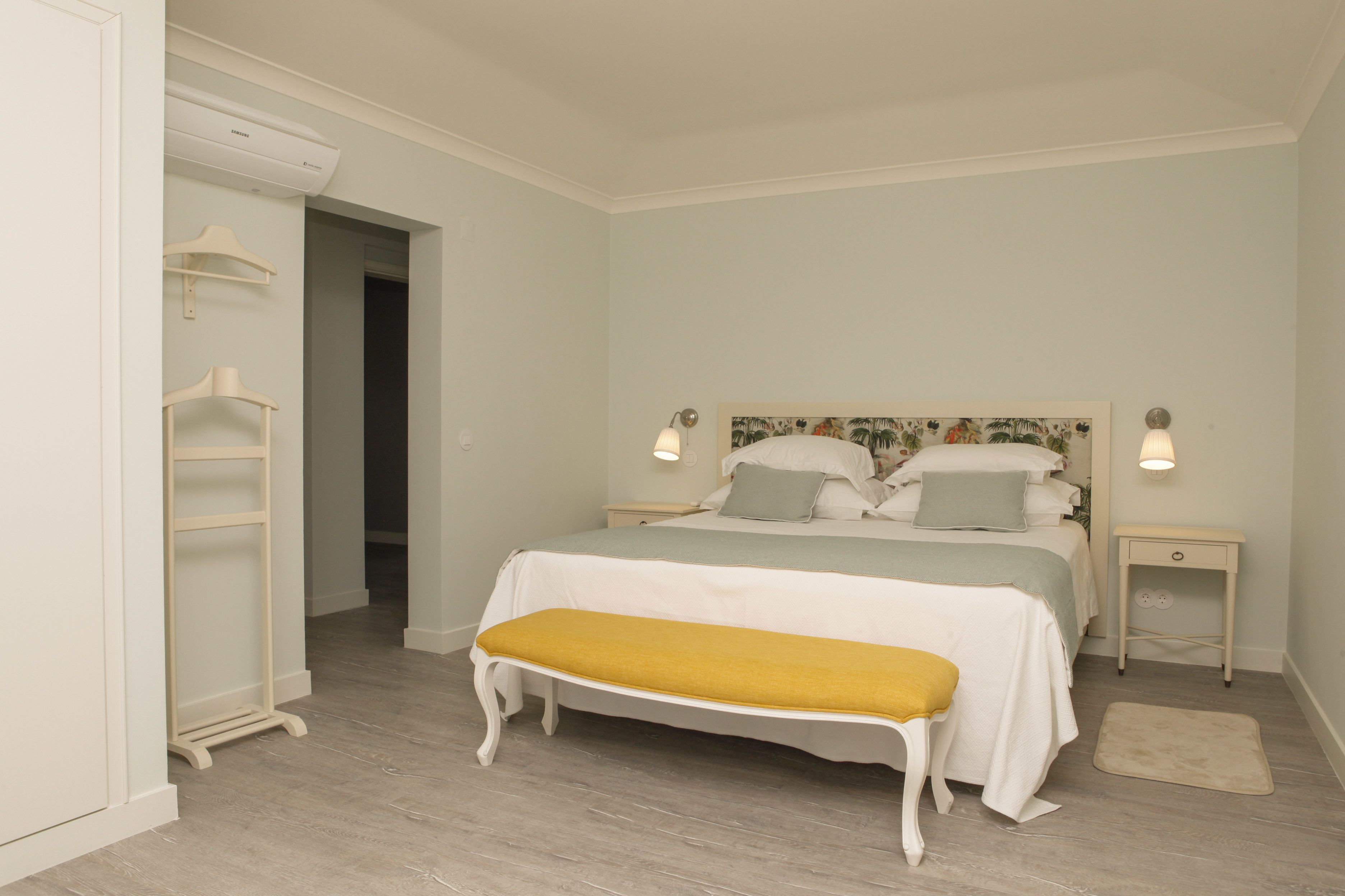 A bedroom with a bed, bedside tables, a bench, and a wardrobe.