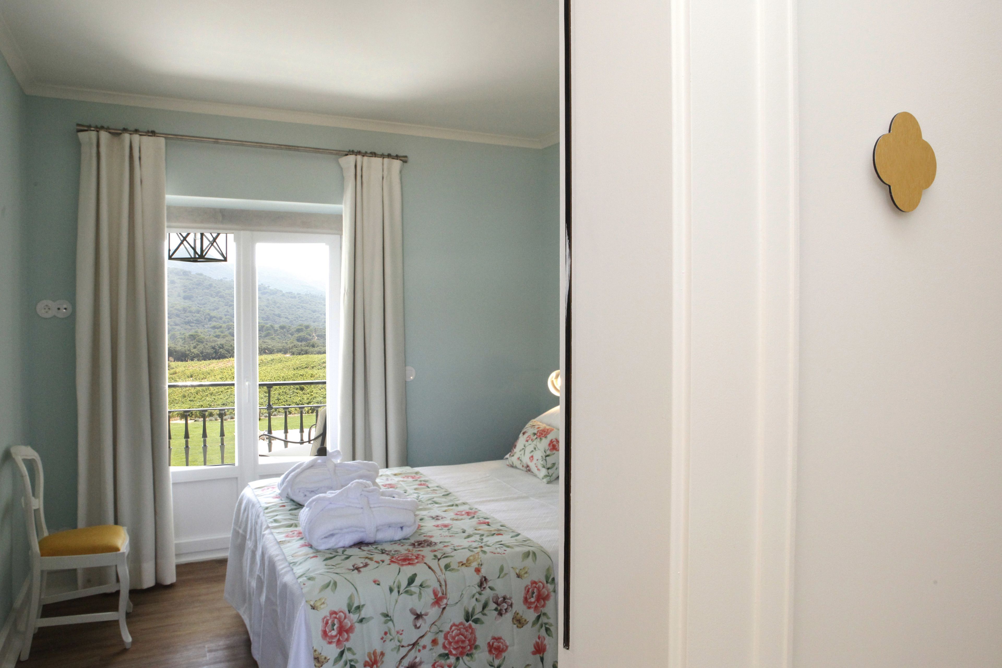 A bedroom with a bed, a chair, and a view of a balcony.