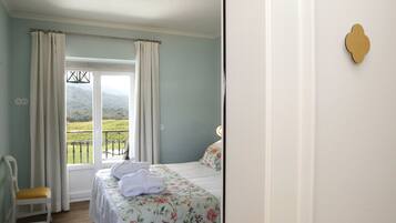 A bedroom with a bed, a chair, and a view of a balcony.