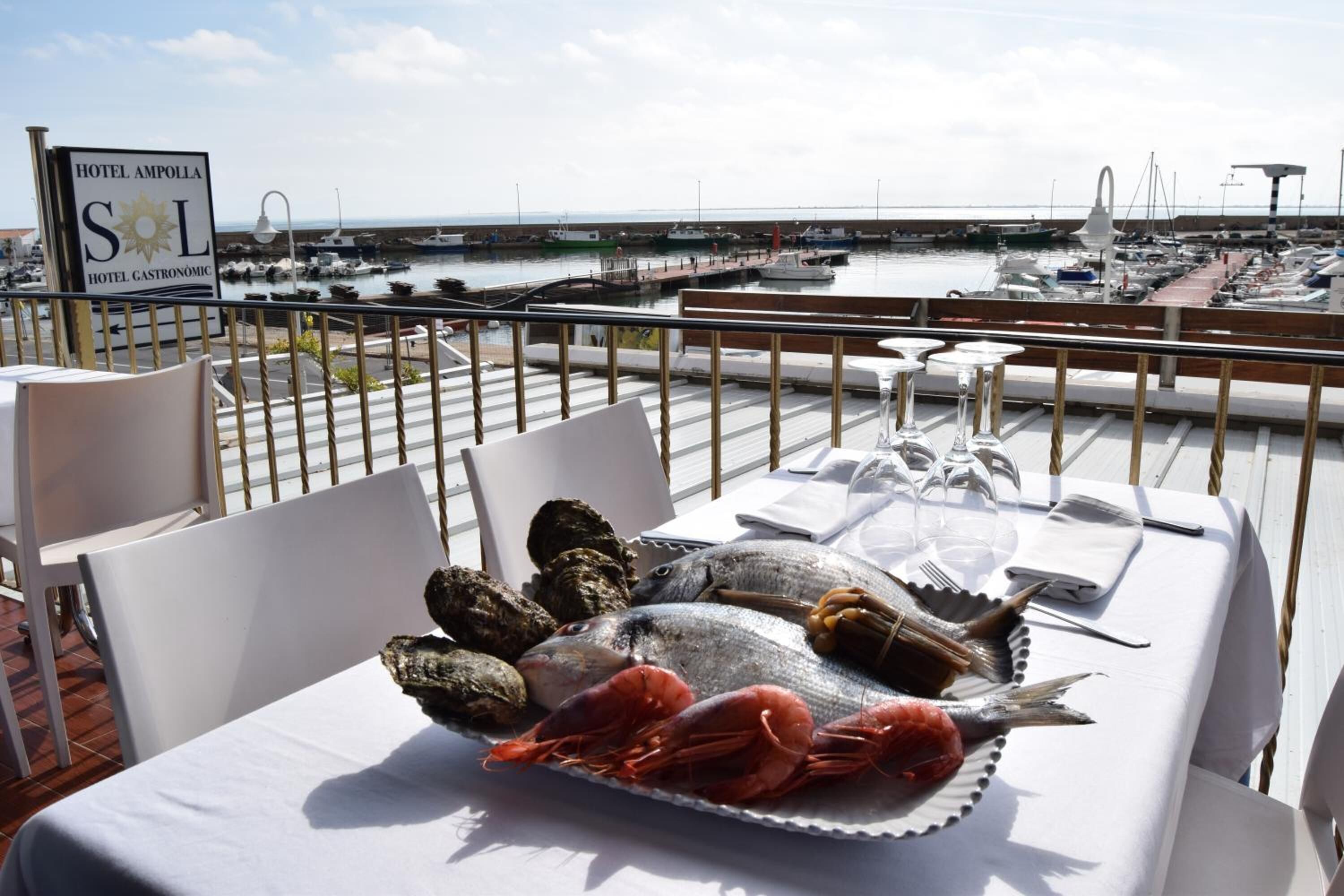 Une table à manger dressée avec des fruits de mer, sur une terrasse donnant sur une marina.