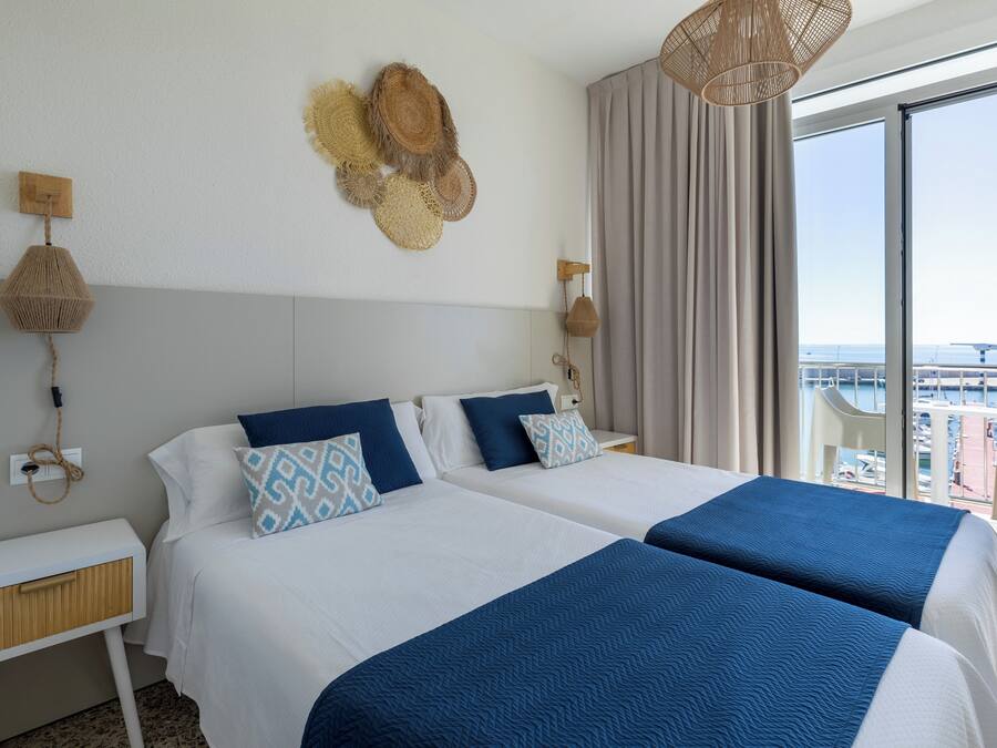 A hotel room with two beds, a large window with a view, and a balcony.