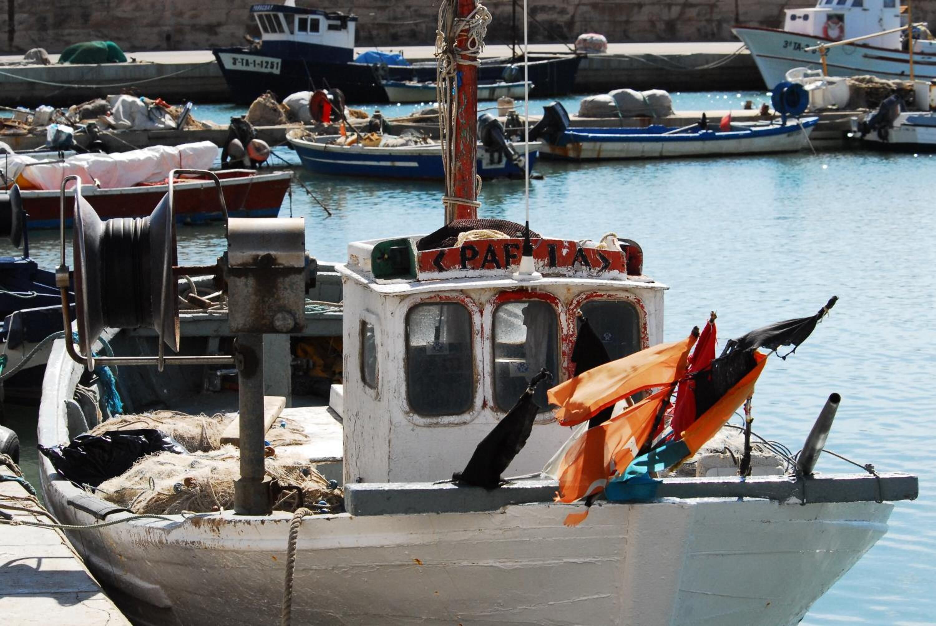 A boat docked at a marina with a name sign reading "PAF 1A".
