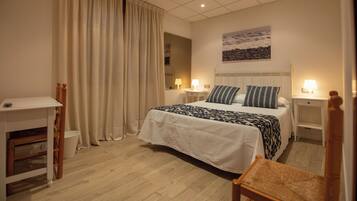 Habitación de hotel con cama, mesitas de noche, escritorio, silla, cortina y un cuadro en la pared.