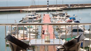 A balcony with a table and chairs overlooking a marina with boats. - Hotel Ampolla Sol (L'Ampolla)