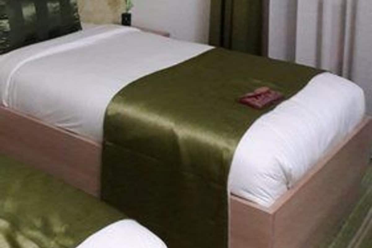 A hotel room with a bed, a bedside table, and a window with curtains.