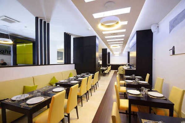 A modern restaurant with long communal tables and yellow chairs, featuring a bright and clean interior. - Hani Hotel (Algiers)