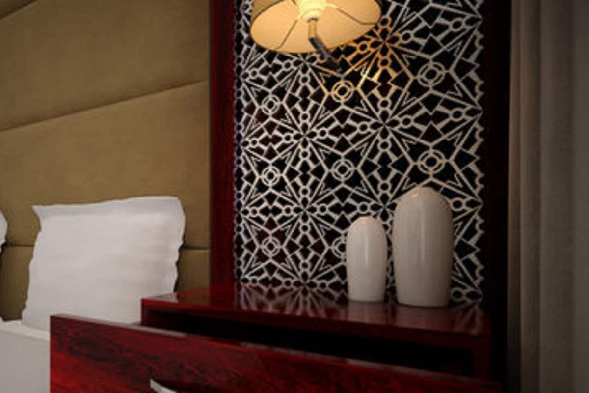 A hotel room with a bed, a nightstand, a lamp, and a decorative wall panel.