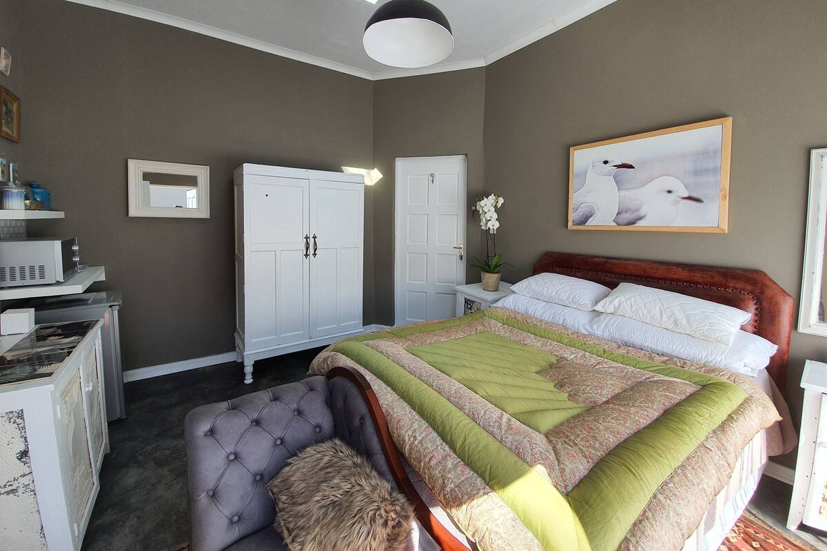 A bedroom with a bed, a wardrobe, a desk, and a chair.
