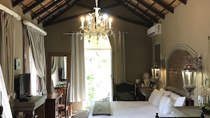 A room with a bed, a desk, a television, and a chandelier. - Waterhouse Guest Lodges 202 Lawley Street (Pretoria)