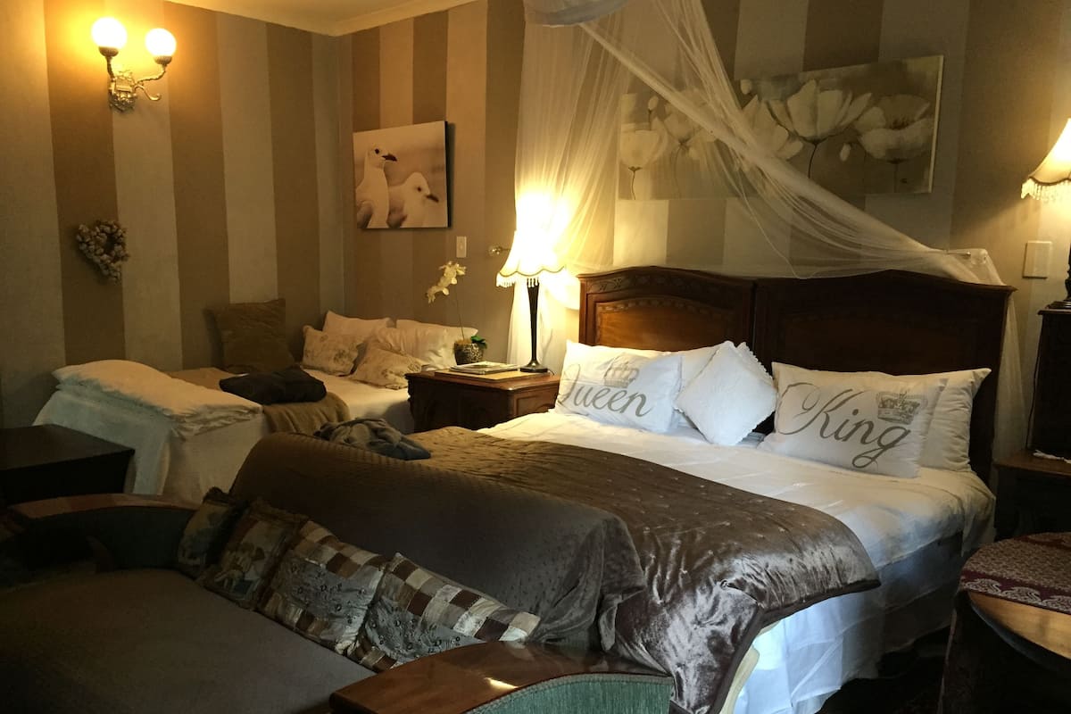A hotel room with a large bed, two bedside tables, a nightstand, a chair, and a decorative wall with a painting.