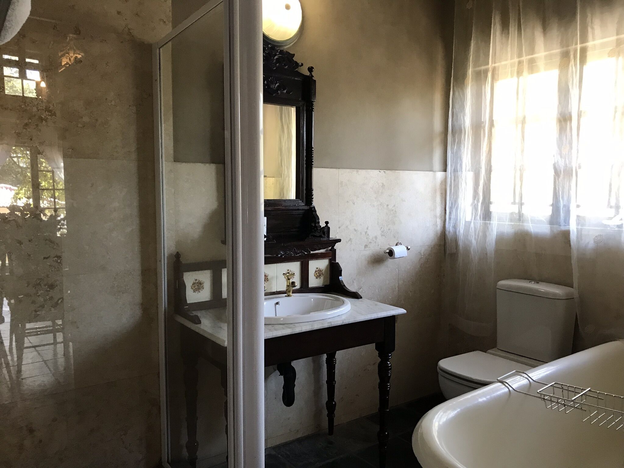 A bathroom with a white sink, dark wooden vanity, a mirror, and a white toilet.