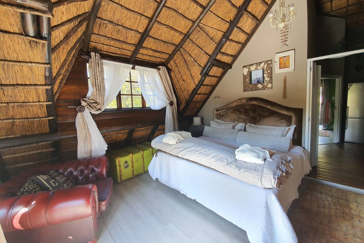 A cozy room with a bed, a red leather chair, and a suitcase.