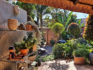 Un jardín con plantas en macetas, una escultura de cabeza de piedra y un muro de ladrillo.