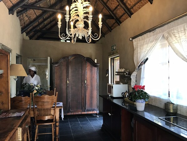 Una cocina con un armario de madera, una araña y una ventana con cortinas.