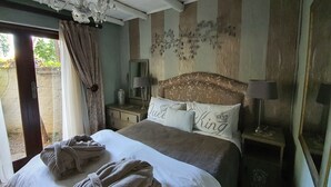 A bedroom with a large bed, two bedside tables, a chandelier, and a window with curtains. - Waterhouse Guest Lodges 295 Indus Street (Pretoria)