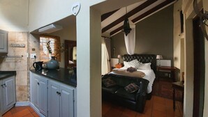 A compact hotel room with a kitchenette, a bed with a canopy, and a small sitting area. - Waterhouse Guest Lodges 295 Indus Street (Pretoria)