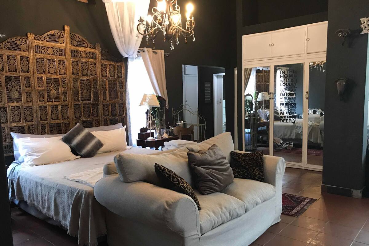 Ein Schlafzimmer mit einem großen Bett, einer Couch, einer Chandelier und einem Kleiderschrank.