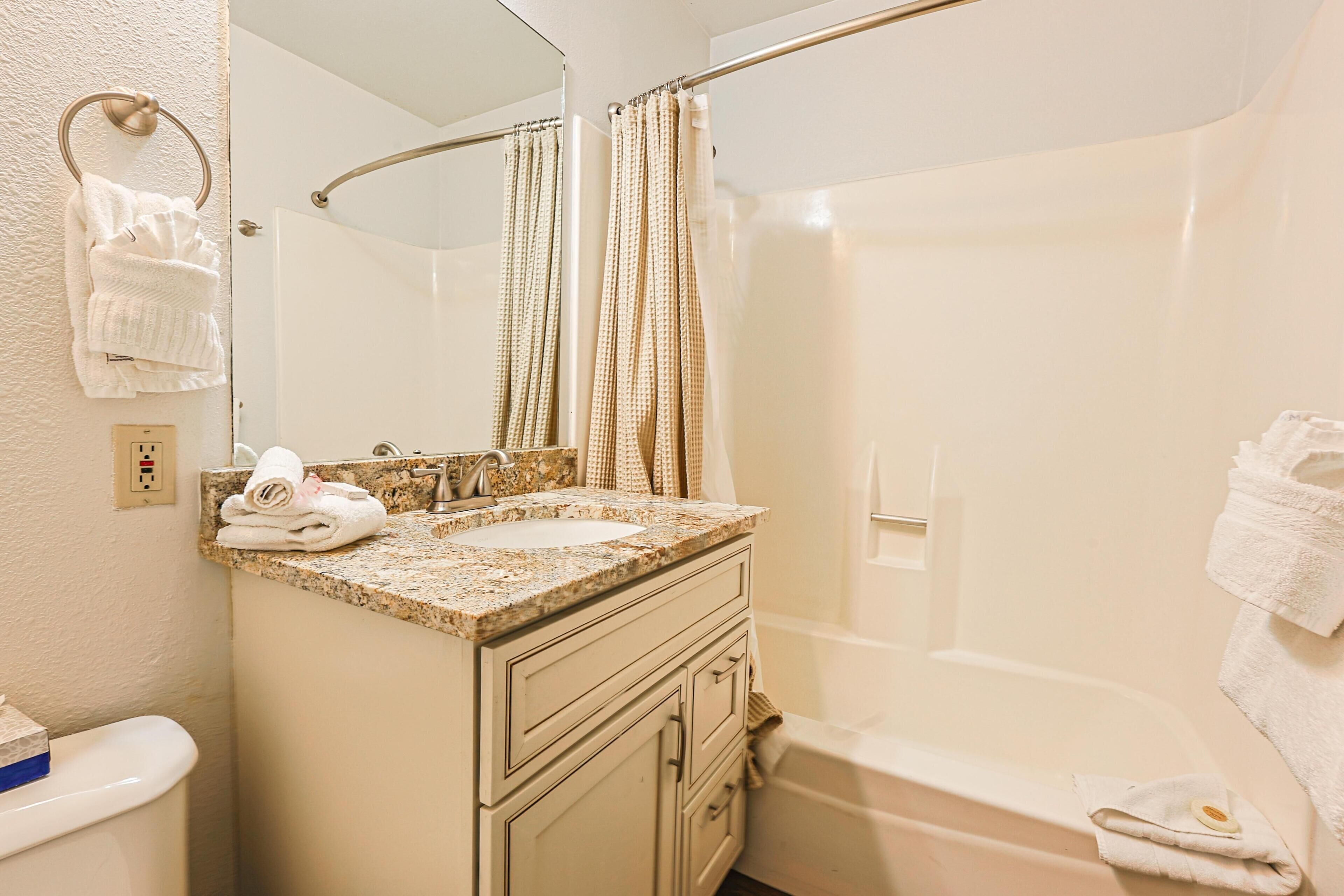 Une salle de bain équipée d’un lavabo, d’un miroir, d’un porte-serviettes et d’une baignoire.