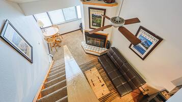 A staircase leading to a living area with a fireplace, a ceiling fan, and framed pictures on the walls.