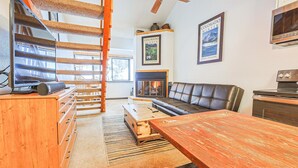 Una sala de estar con chimenea, un sofá, una mesa de madera y una escalera.