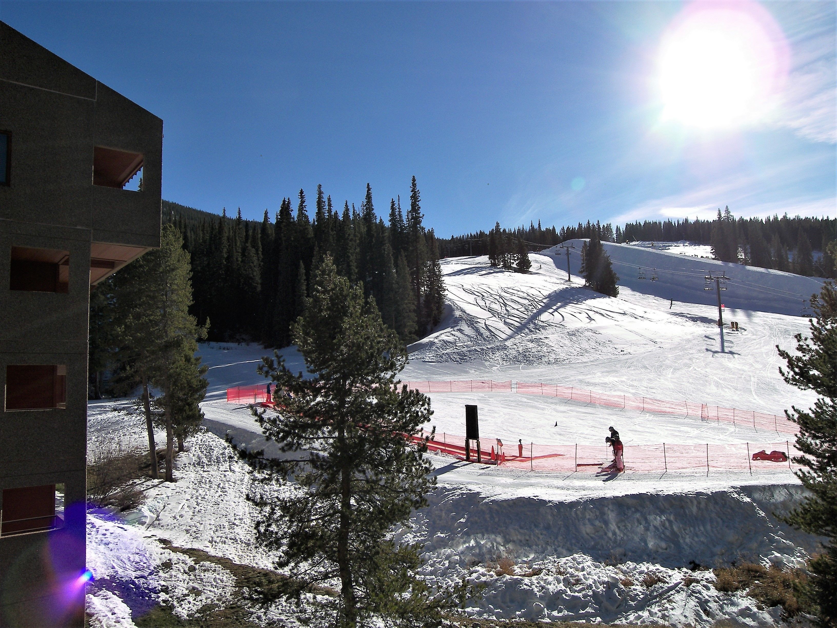A snow-covered ski slope with a building in the foreground.