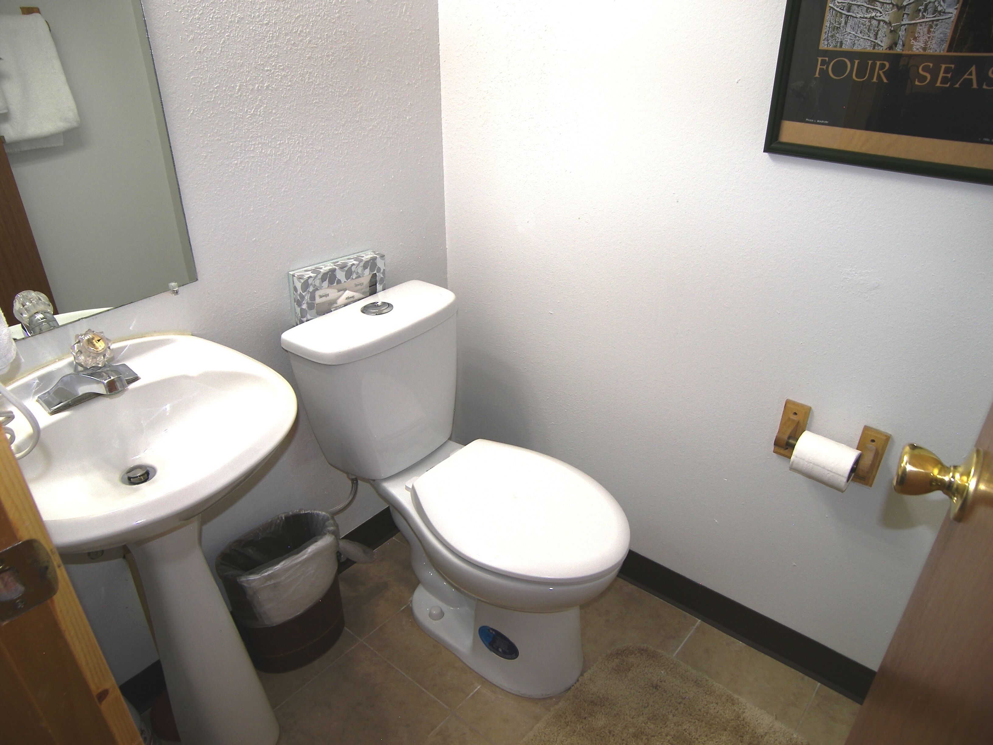Un baño con lavamanos, inodoro y un cuadro en la pared.