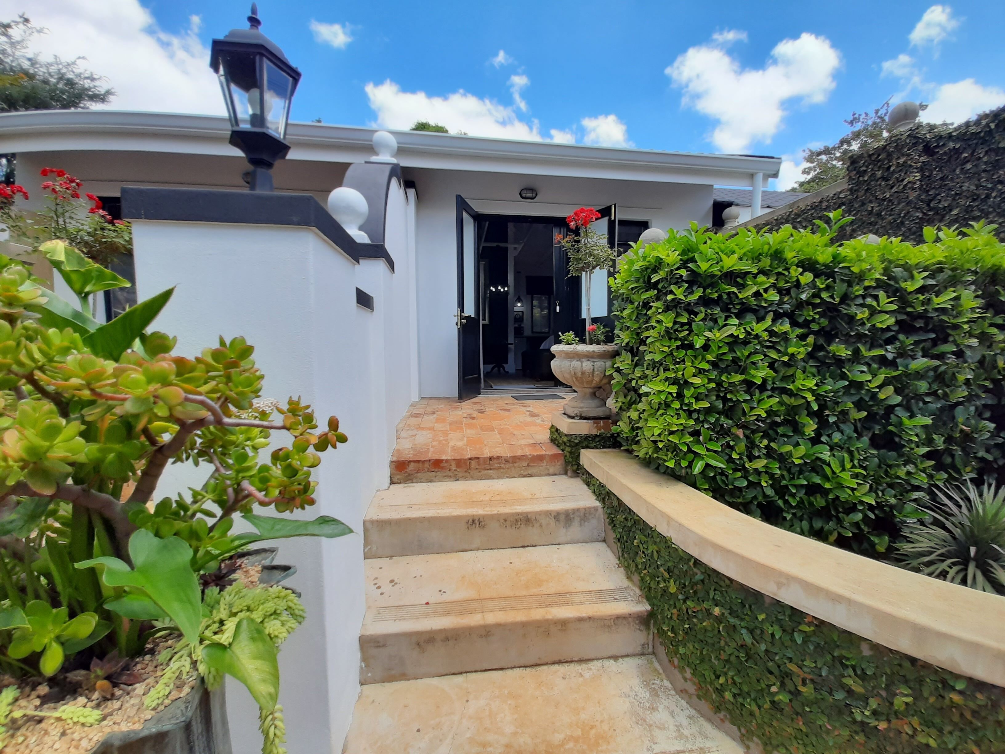 Una casa moderna con fachada blanca, un farol negro y una escalera de piedra que conduce a la entrada.