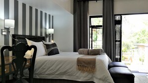 Habitación de hotel con una cama grande, un escritorio, una silla, un ventilador de techo y vistas al exterior.
