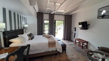 Quarto de hotel com uma cama grande, uma escrivaninha, uma cadeira, uma televisão e vista para o exterior.