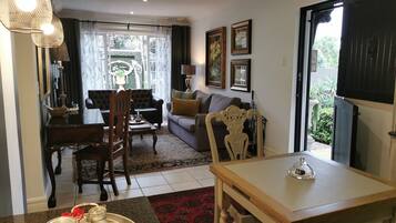 Sala de estar con comedor, que incluye un sofá, sillas, una mesa y vistas al exterior.