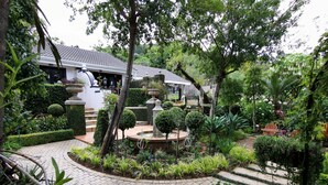 Un jardín bien cuidado con una fuente, setos podados y un camino empedrado.