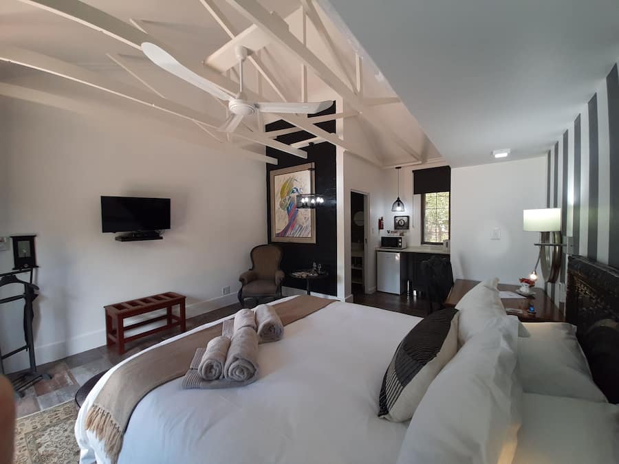 A hotel room with a large bed, a TV, a painting, a desk, and a chair.