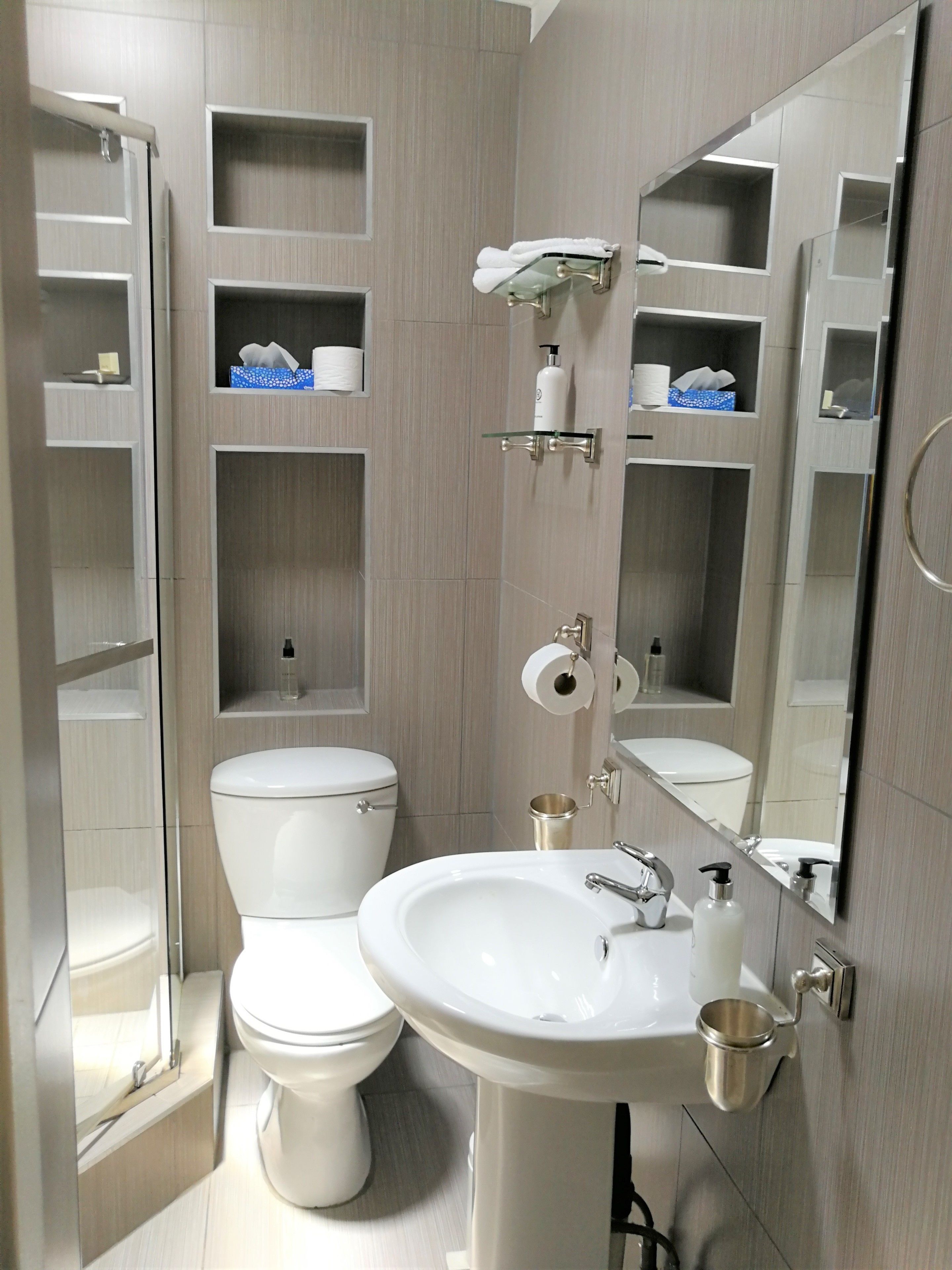 A modern bathroom with a toilet, sink, and built-in shelves.