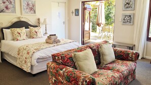 Ein Schlafzimmer mit einem Bett, einem blumengedeckten Sofa und einer Tür, die auf einen Balkon führt.
